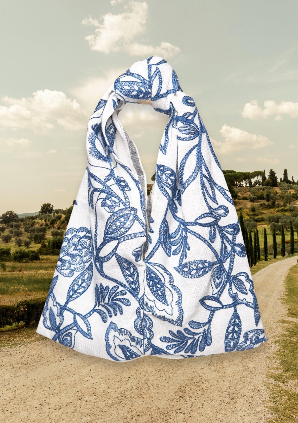 Blue floral patterned Knot Bag, upcycled from deadstock fabric, on a path with a scenic background