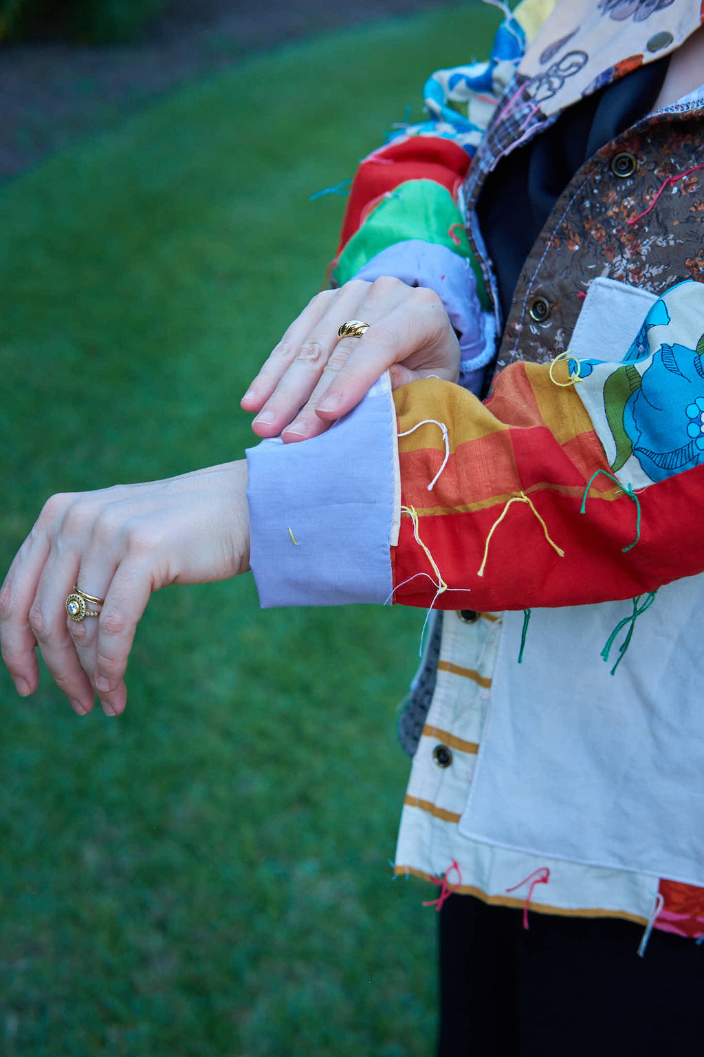 Person wearing an upcycled colorful jacket made from a quilt with a green background.