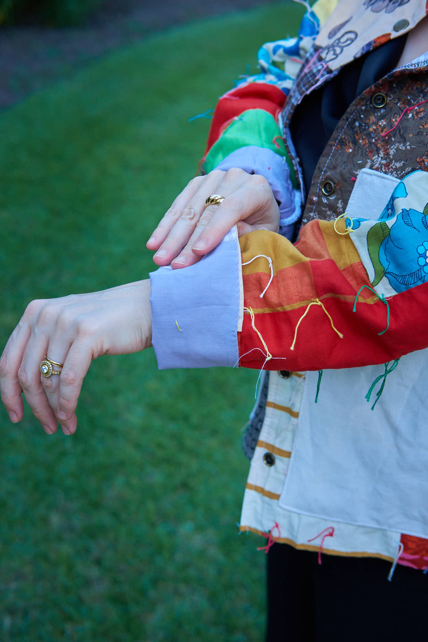 Person wearing an upcycled colorful jacket made from a quilt with a green background.