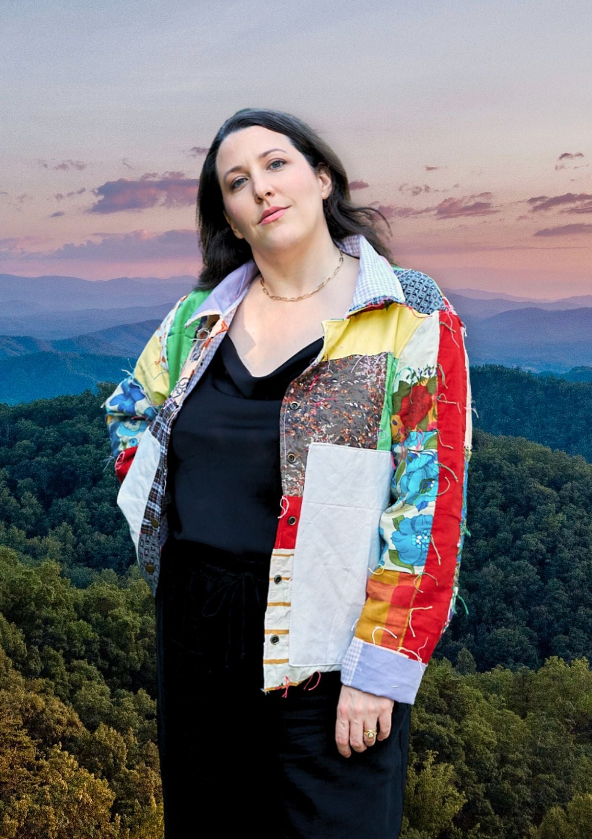 Woman wearing a colorful upcycled quilted patchwork jacket with a scenic background of mountains and trees.