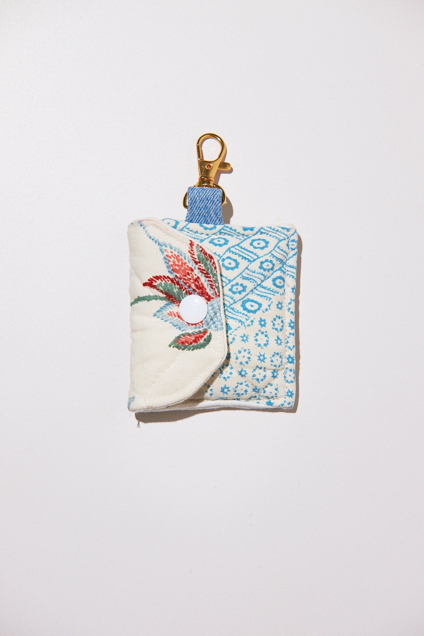 Small fabric pouch with floral design and keychain clip upcycled from quilt on a white background
