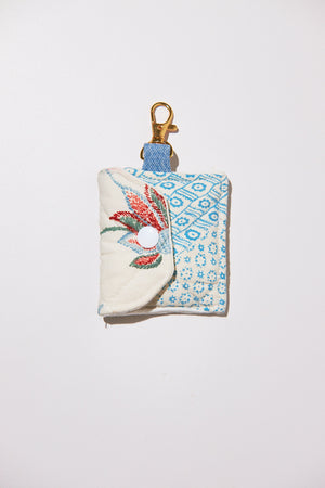 Small fabric pouch with floral design and keychain clip upcycled from quilt on a white background