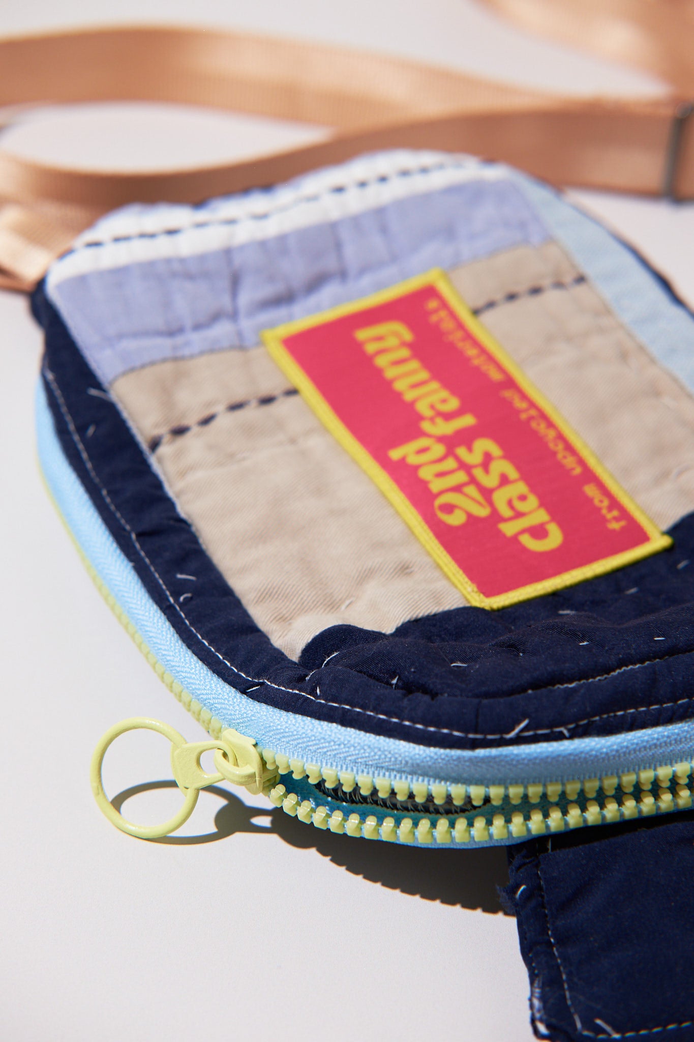 Upclose fanny / crossbody bag with a visible brand label and yellow/blue zipper on a light background
