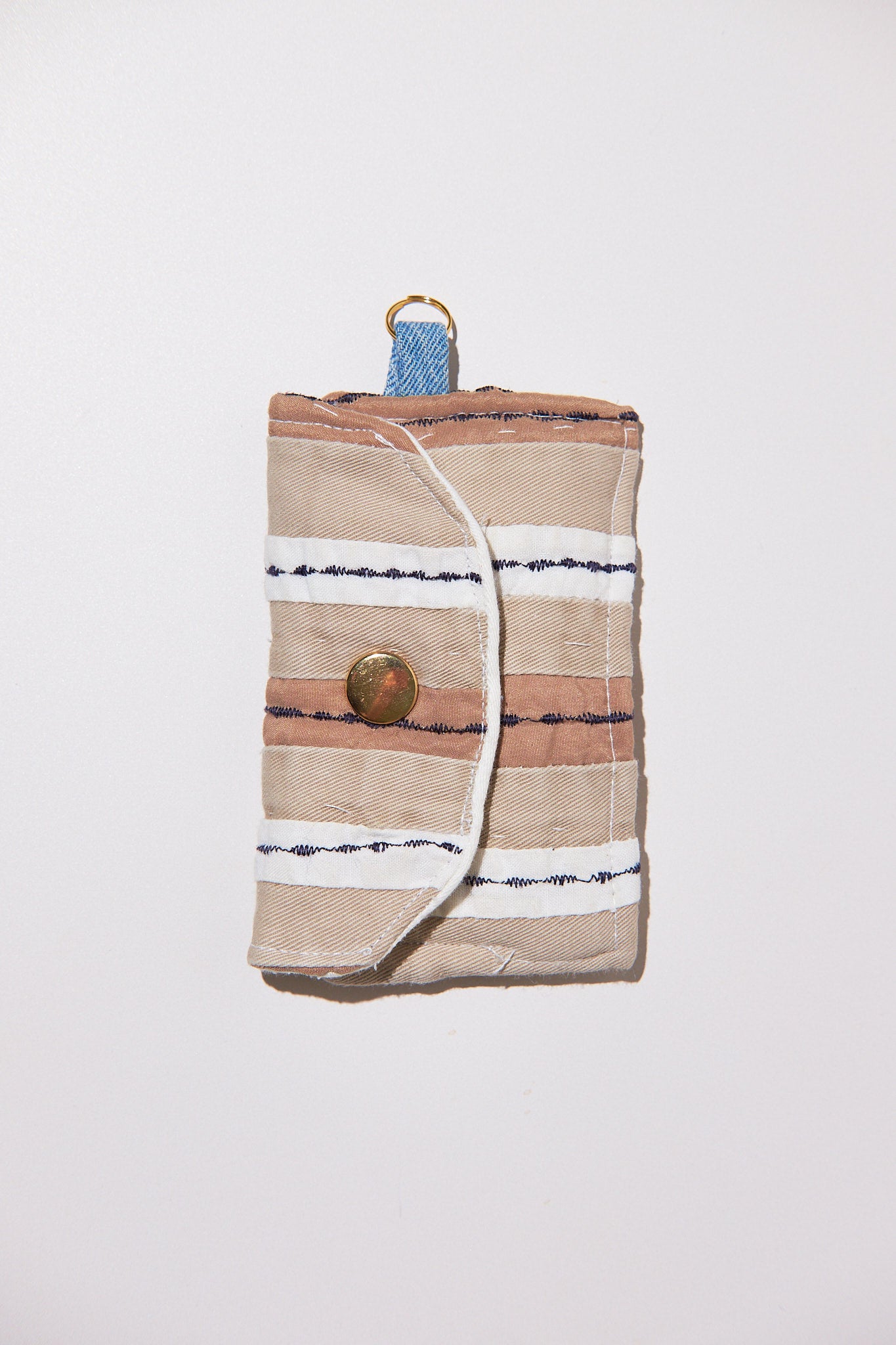 Striped fabric roll with brass button upcycled from comforter on a white background