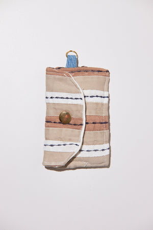 Striped fabric roll with brass button upcycled from comforter on a white background