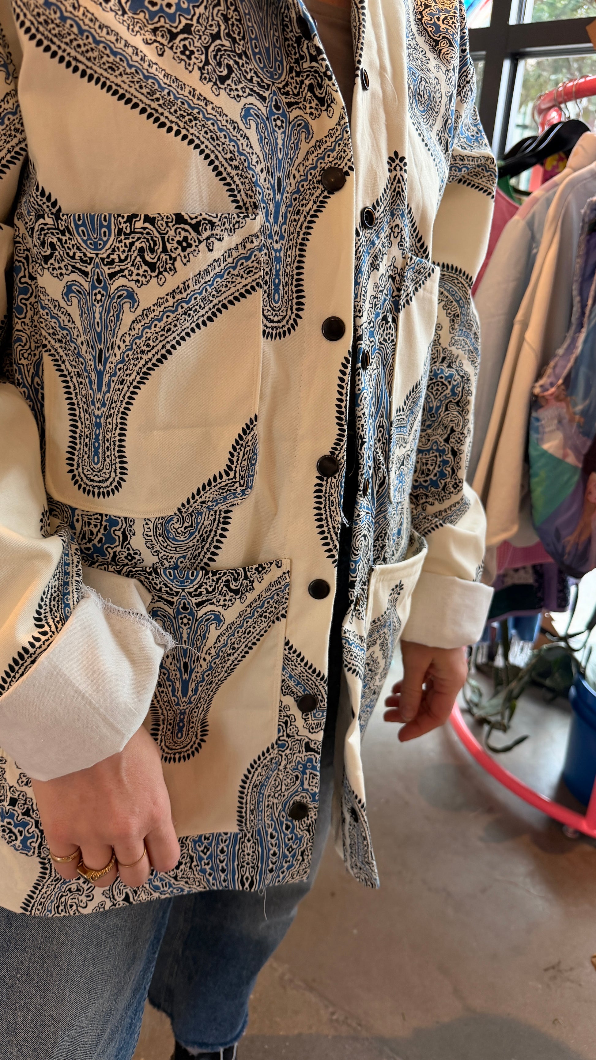 Person wearing a patterned jacket with 4 pockets upcycled from a curtain a blurred background