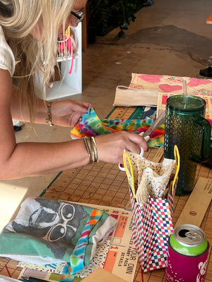 Person holding a colorful bag over a table with various items including a water bottle and a can.
