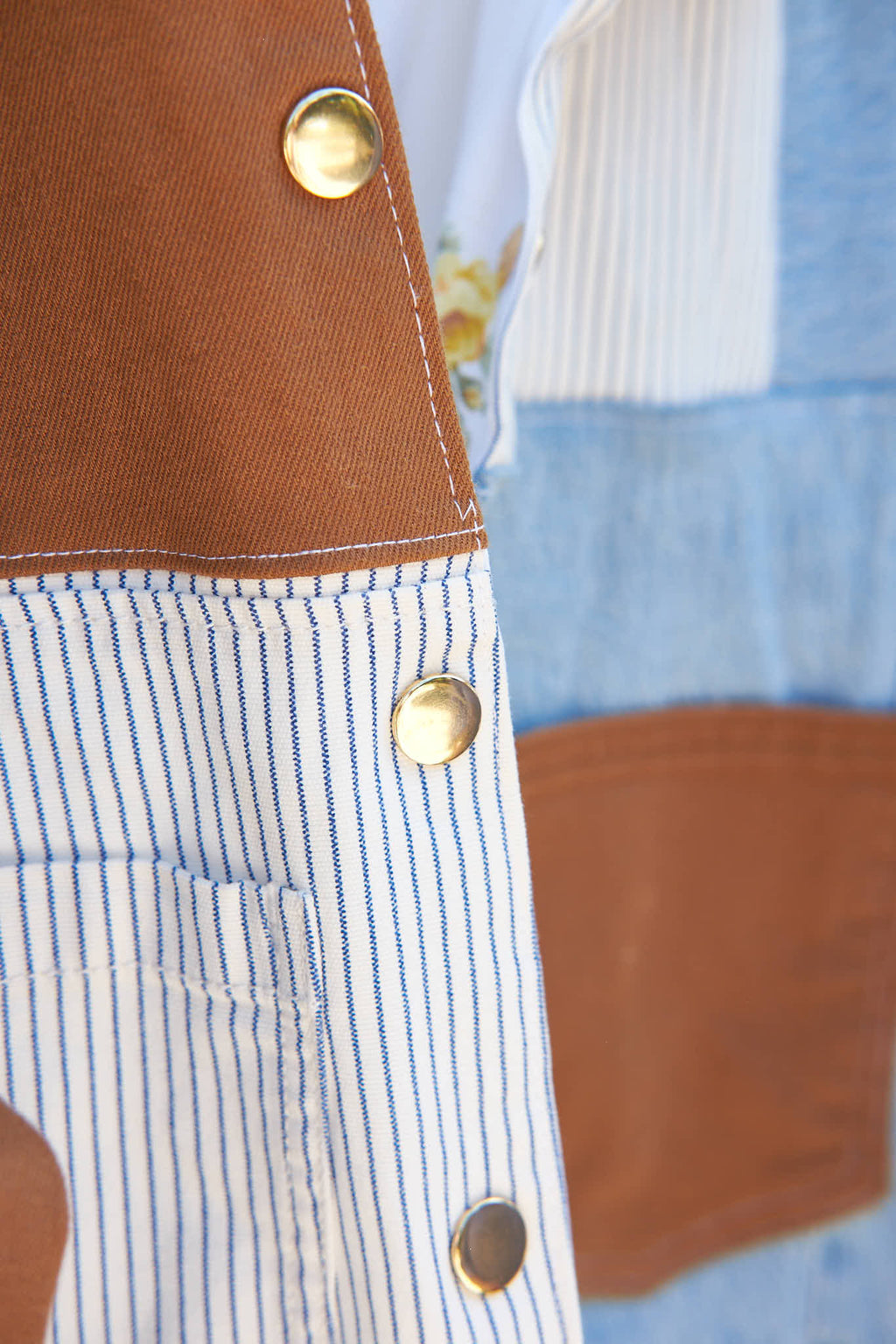 Close-up of a gold snap buttons on a denim patchwork jacket, upcycled from denim jeans.