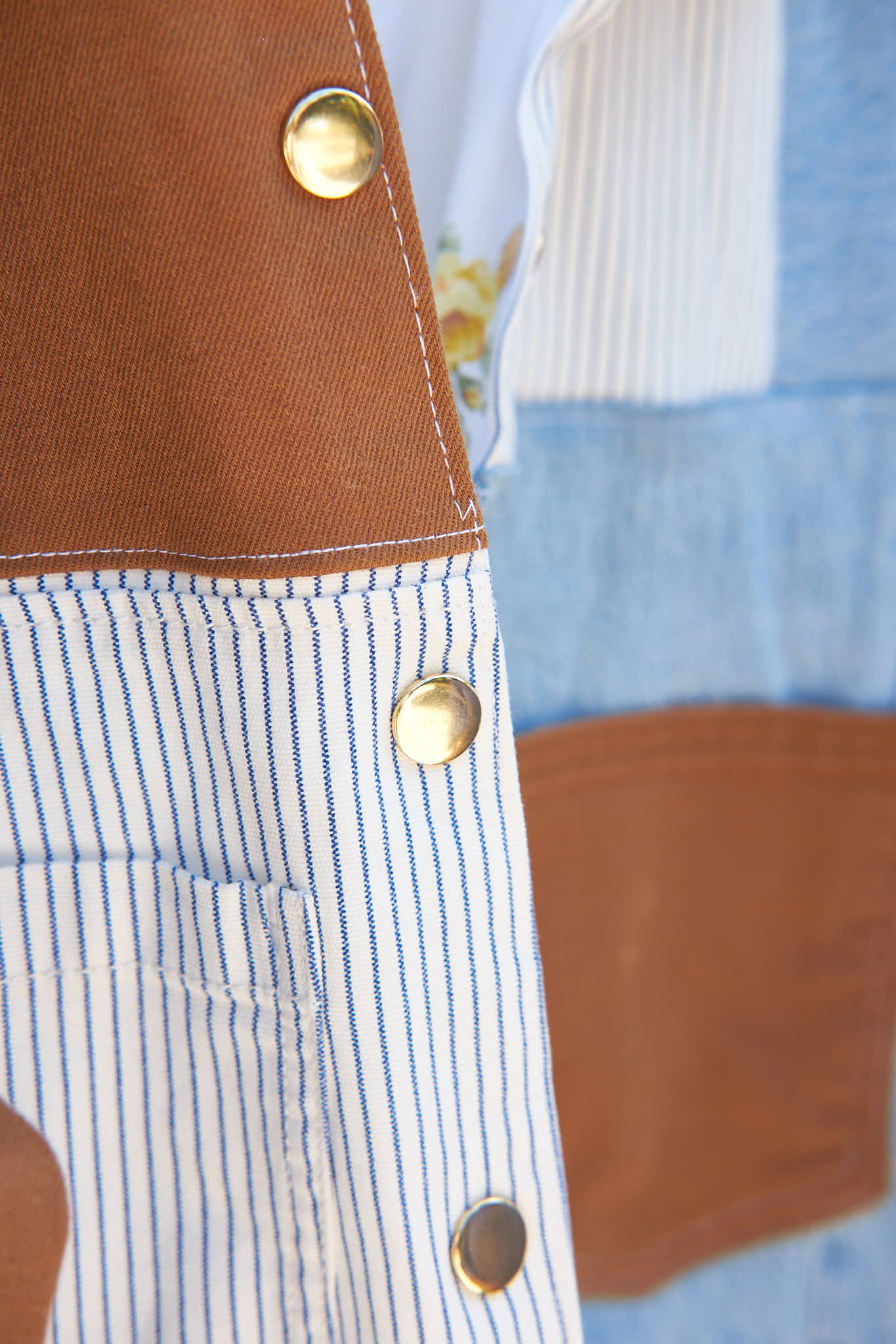 Close-up of a gold snap buttons on a denim patchwork jacket, upcycled from denim jeans.