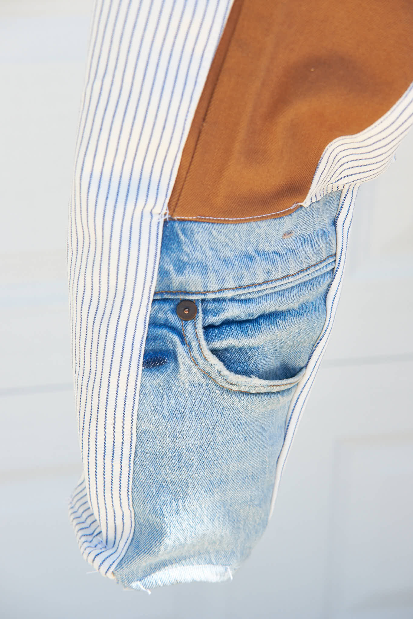 Close-up of denim patchwork jacket sleeve. Upcycled from denim jeans against a gray background.