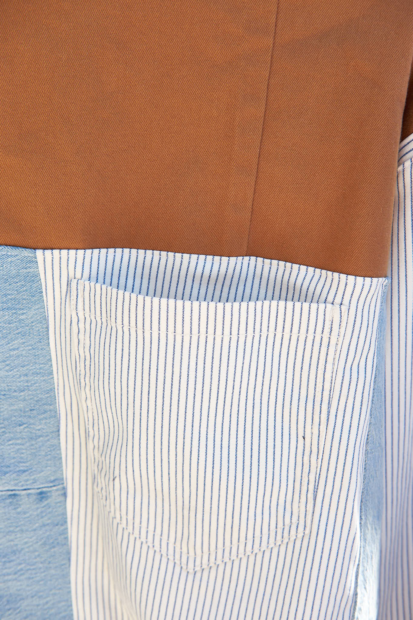 Close-up of a pocket on jacket upcycled from denim jeans with a blue background.
