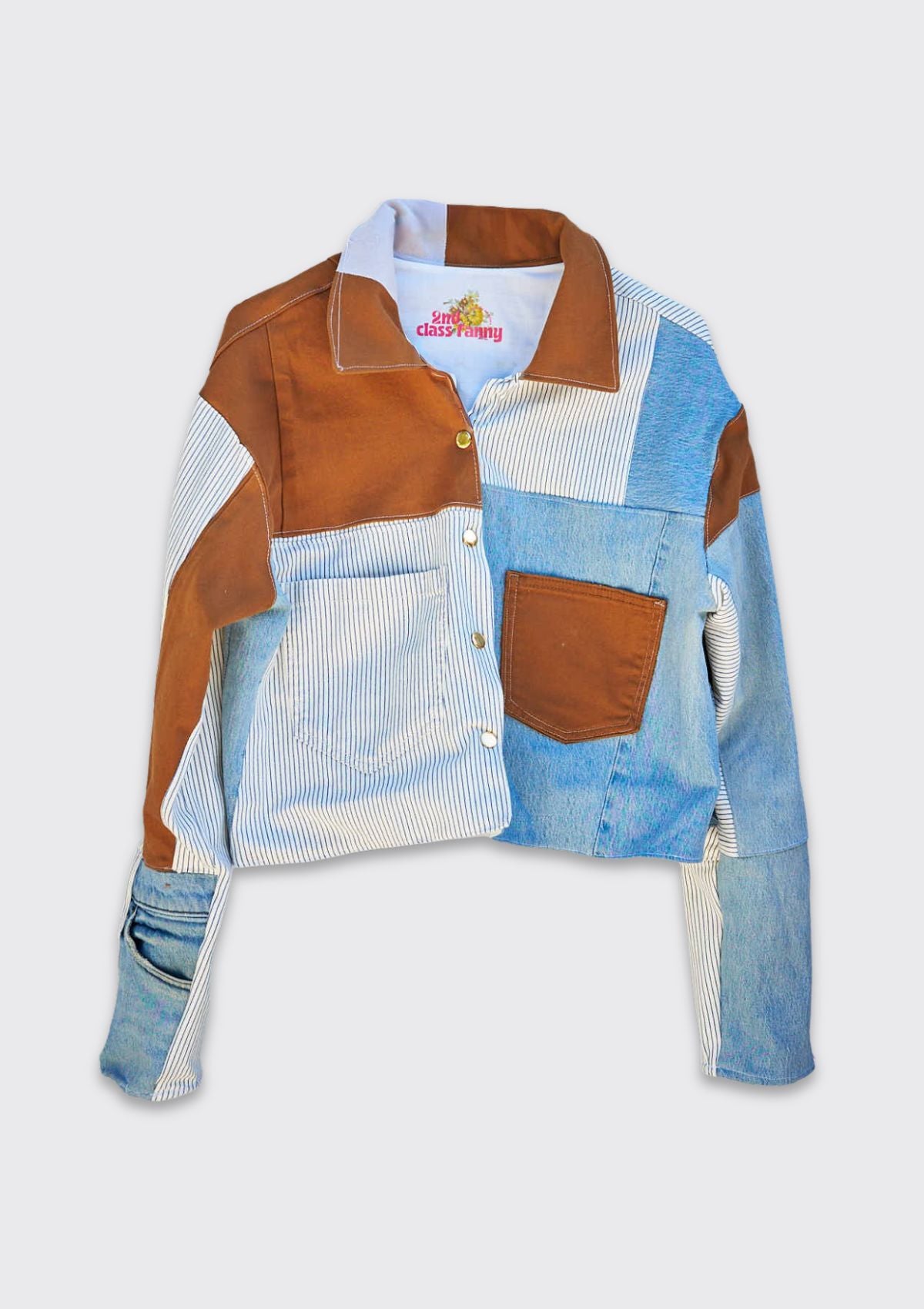 Multicolored denim patchwork jacket with brown, blue, and white sections upcycled from denim jeans on a light gray background.