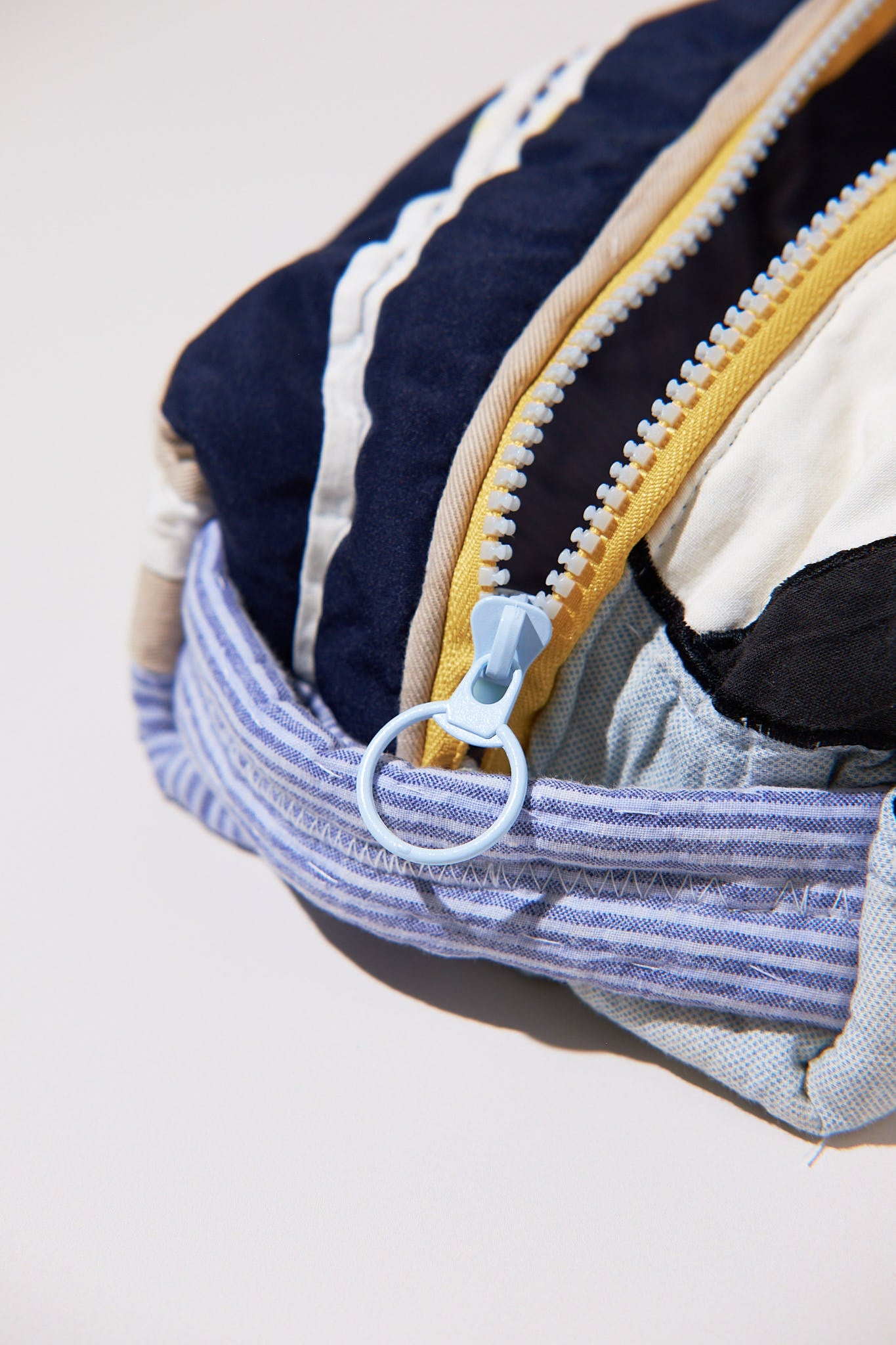 Close-up of a fabric dobb kit with a zipper, upcycld from a quilt showing different colored fabrics inside.