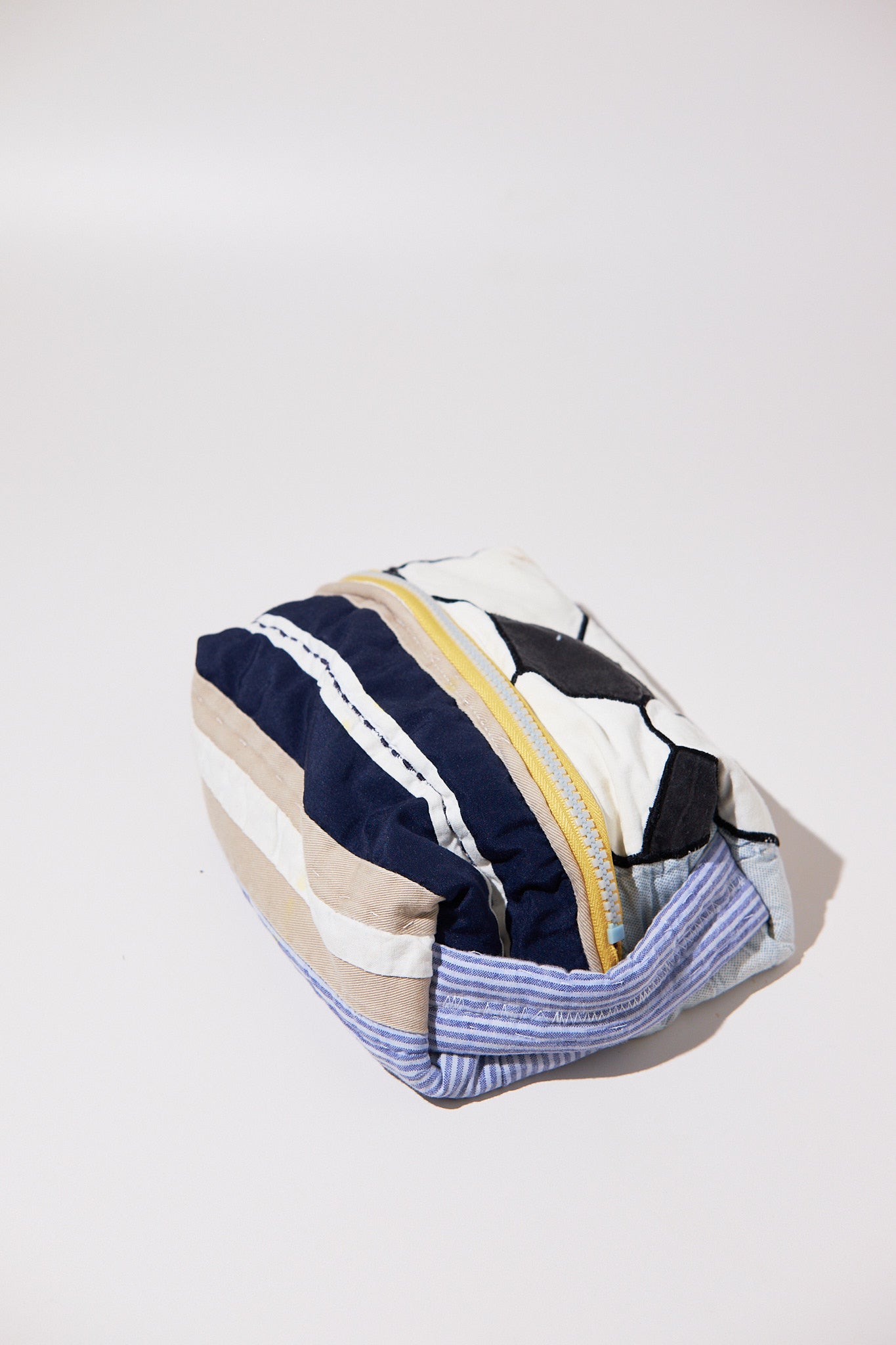 Striped pouch with a zipper and soccer ball upcycled from quilt on a white background