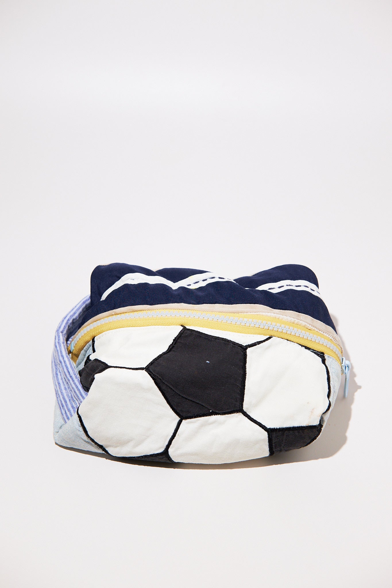 Soccer ball-shaped dobb kit with a zipper made from upcycled quilt on a white background