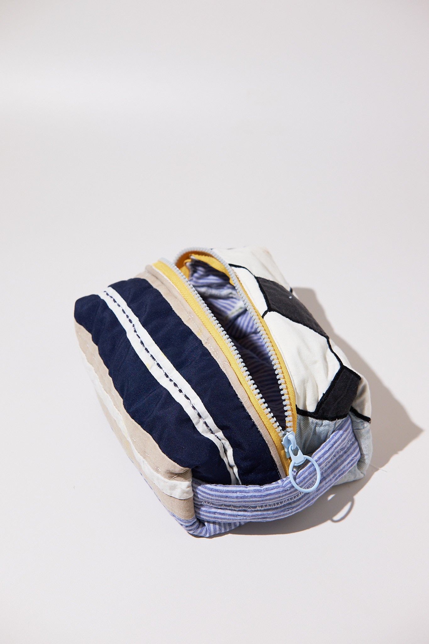Fabric dobb kit with striped pattern , soccer ball and yellow zipper upcycled from a quilt on a light background