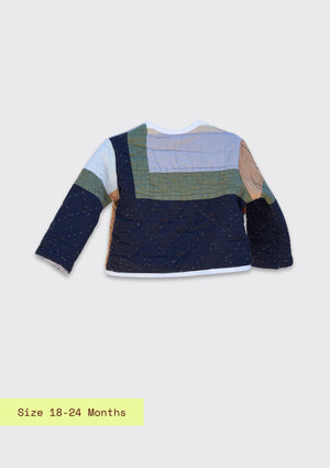 Backside view of children's jacket upcycled from a quilt with a light and dark blue and green pattern on a light gray background