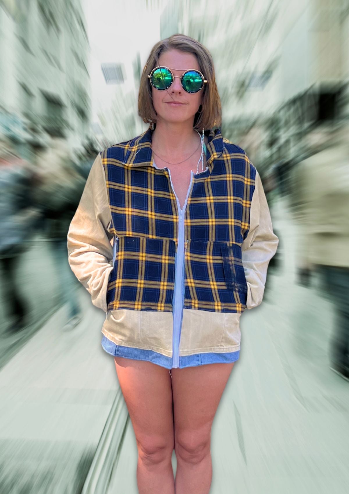 Person wearing a denim and plaid flannel jacket with a blurred street background