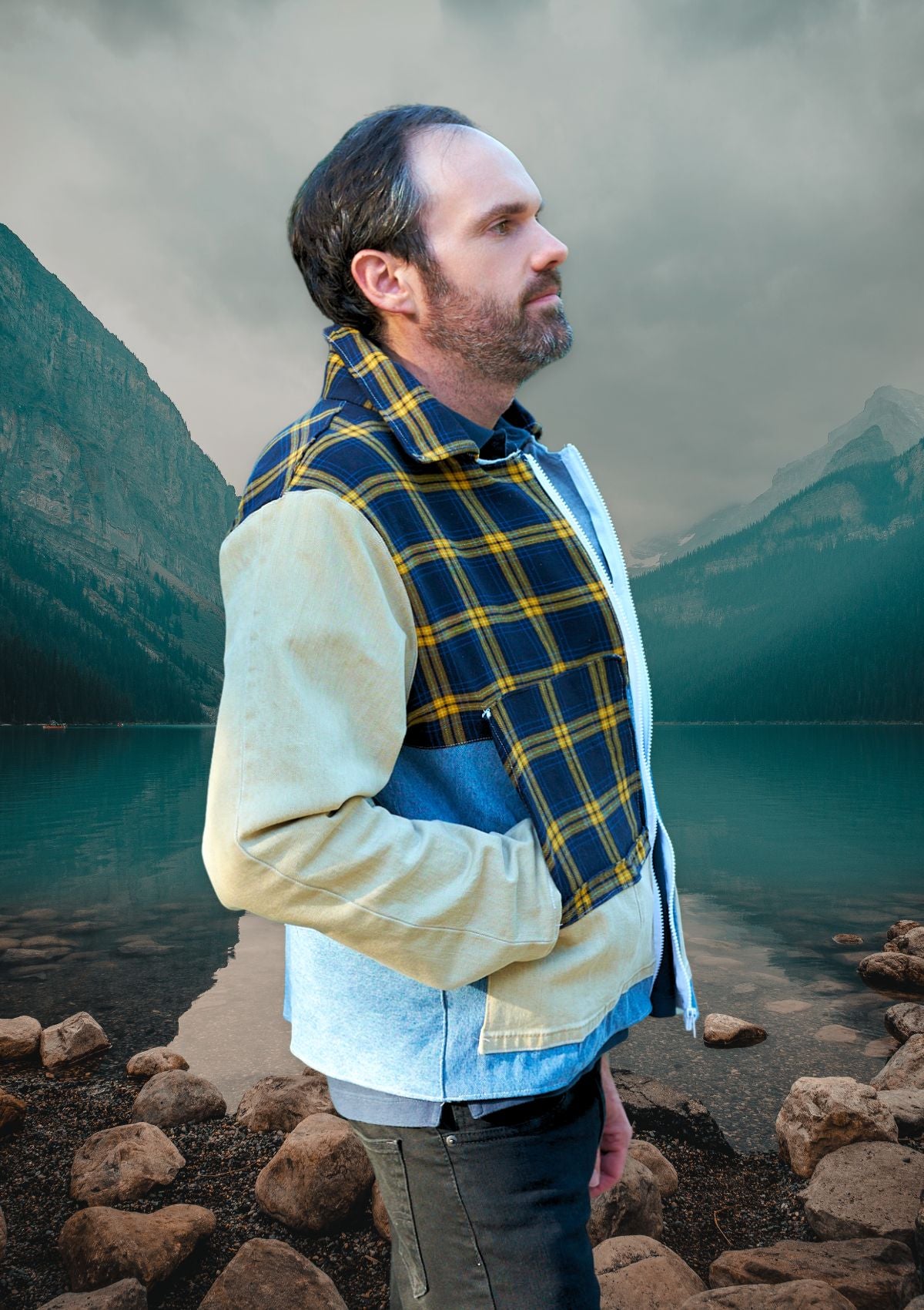 Man wearing an upycycled plaid and denim jacket over a light-colored shirt with a mountainous landscape in the background