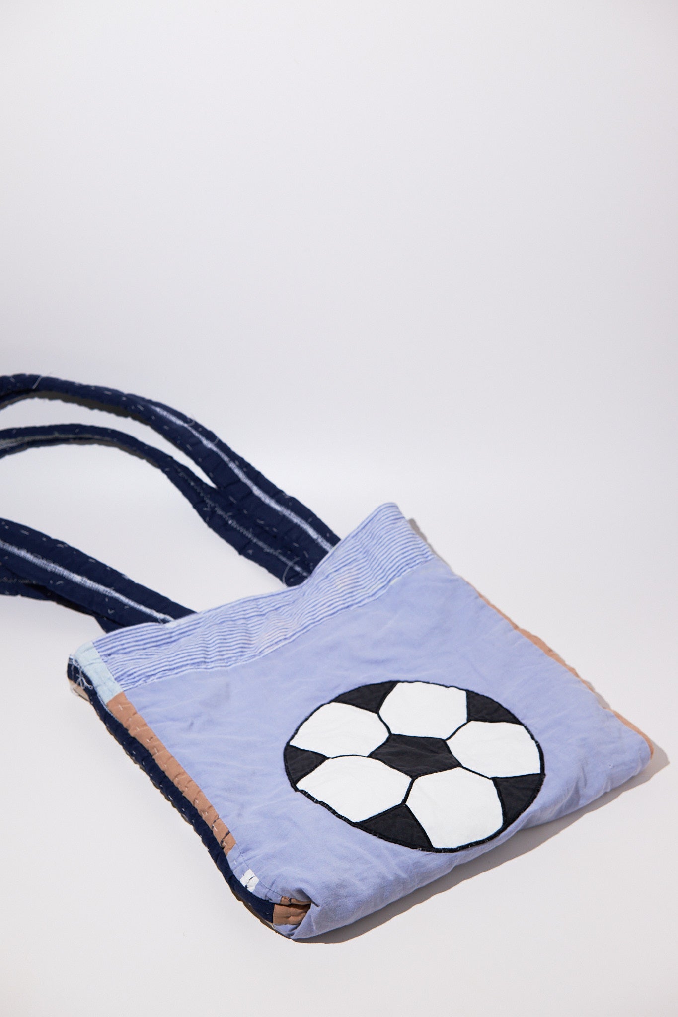 Light blue bag with a soccer ball design made of upcycled quilt on a white background
