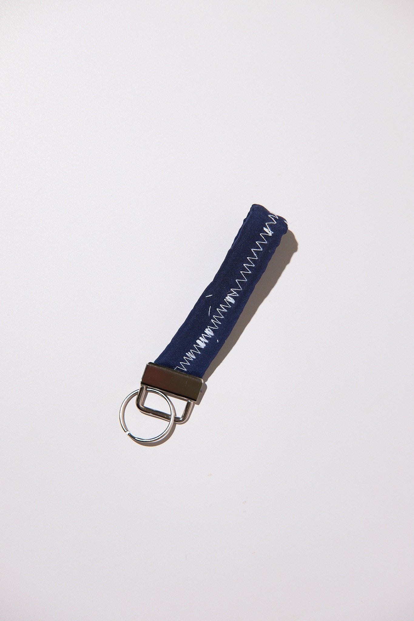Keychain with blue fabric strap and metal ring upcyled from comforter on a white background