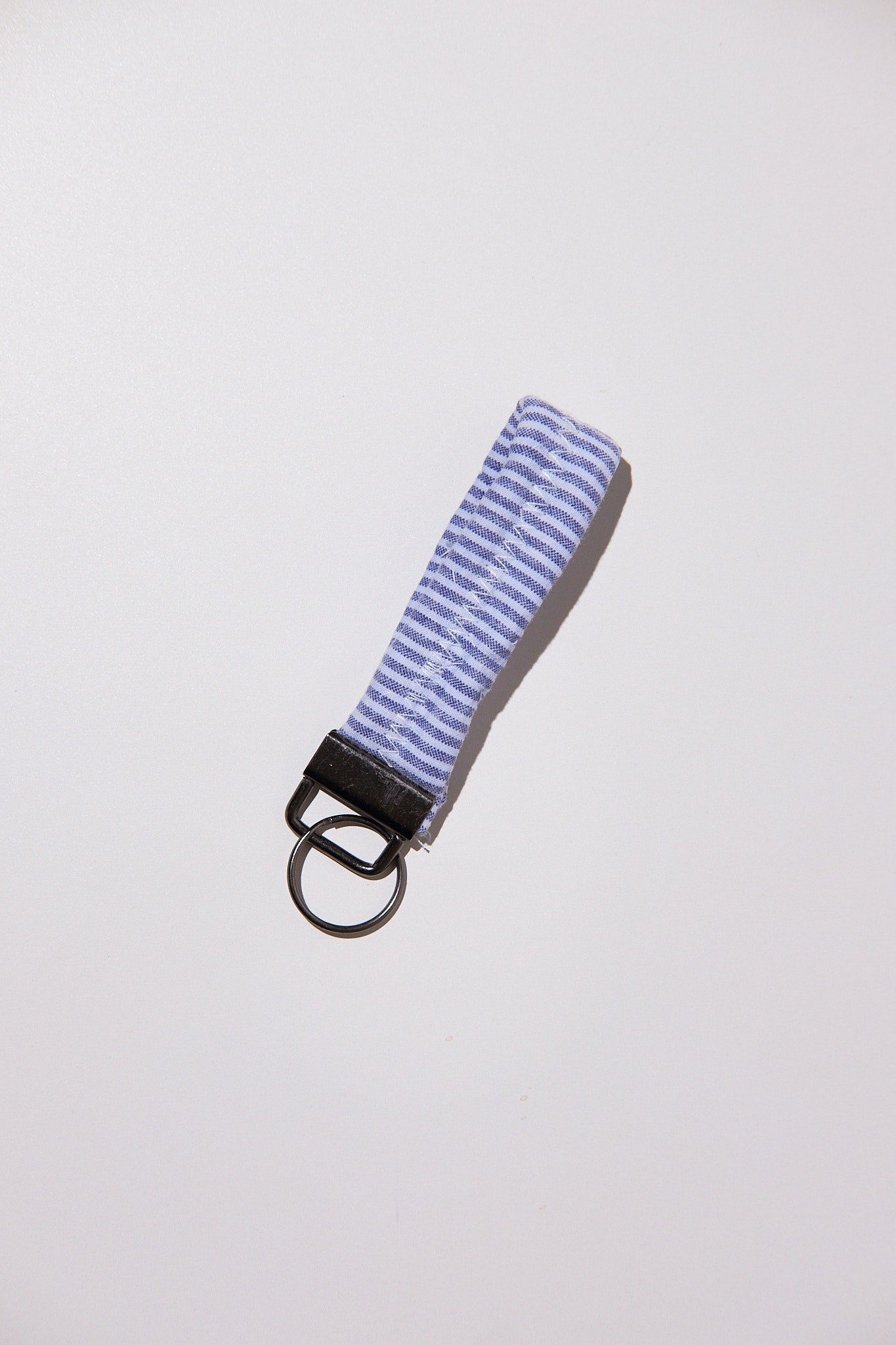 Keychain with striped blue strap upcycled comforter on a light gray background
