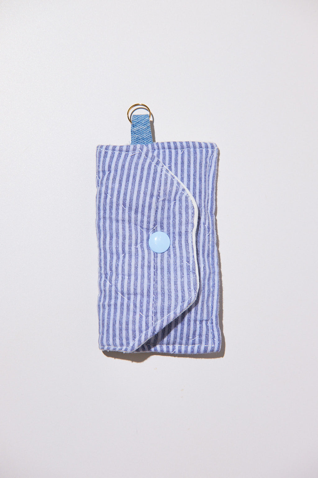 Blue striped key chain pouch with a button and strap upcycled from comforter on a light gray background