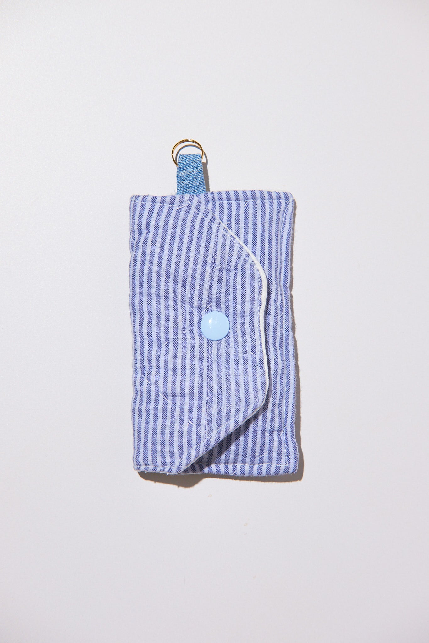 Blue striped key chain pouch with a button and strap upcycled from comforter on a light gray background