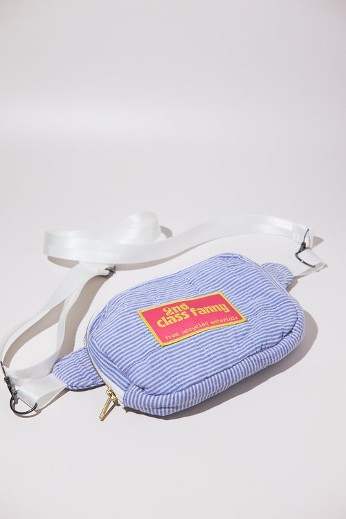 Blue striped seersucker fanny pack / crossbody bag upcycled from comforter with a yellow label and zipper on a white background