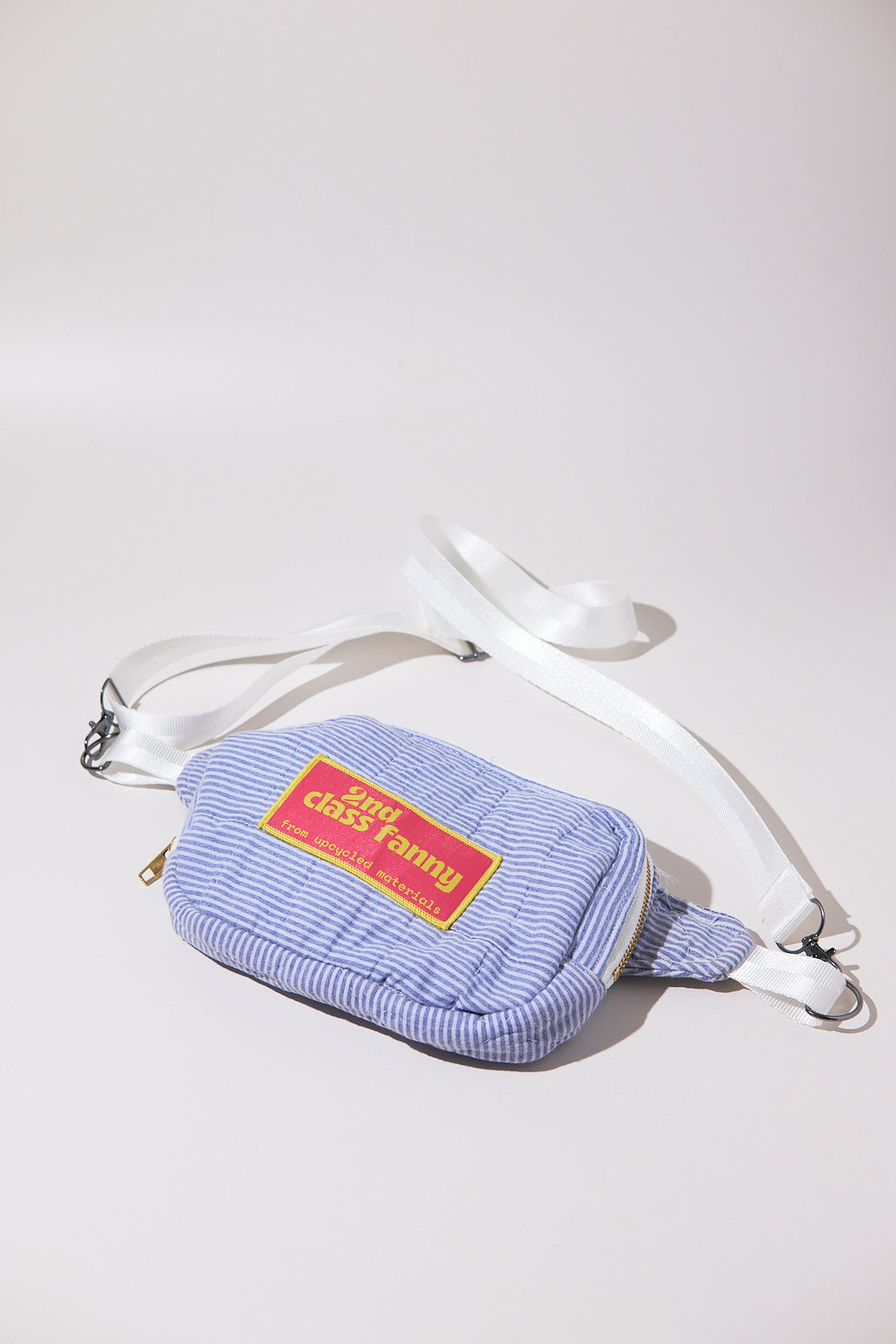 Crossbody bag / Fanny pack in blue striped seersucker pattern with a red label reads 2nd Class Fanny on a white background