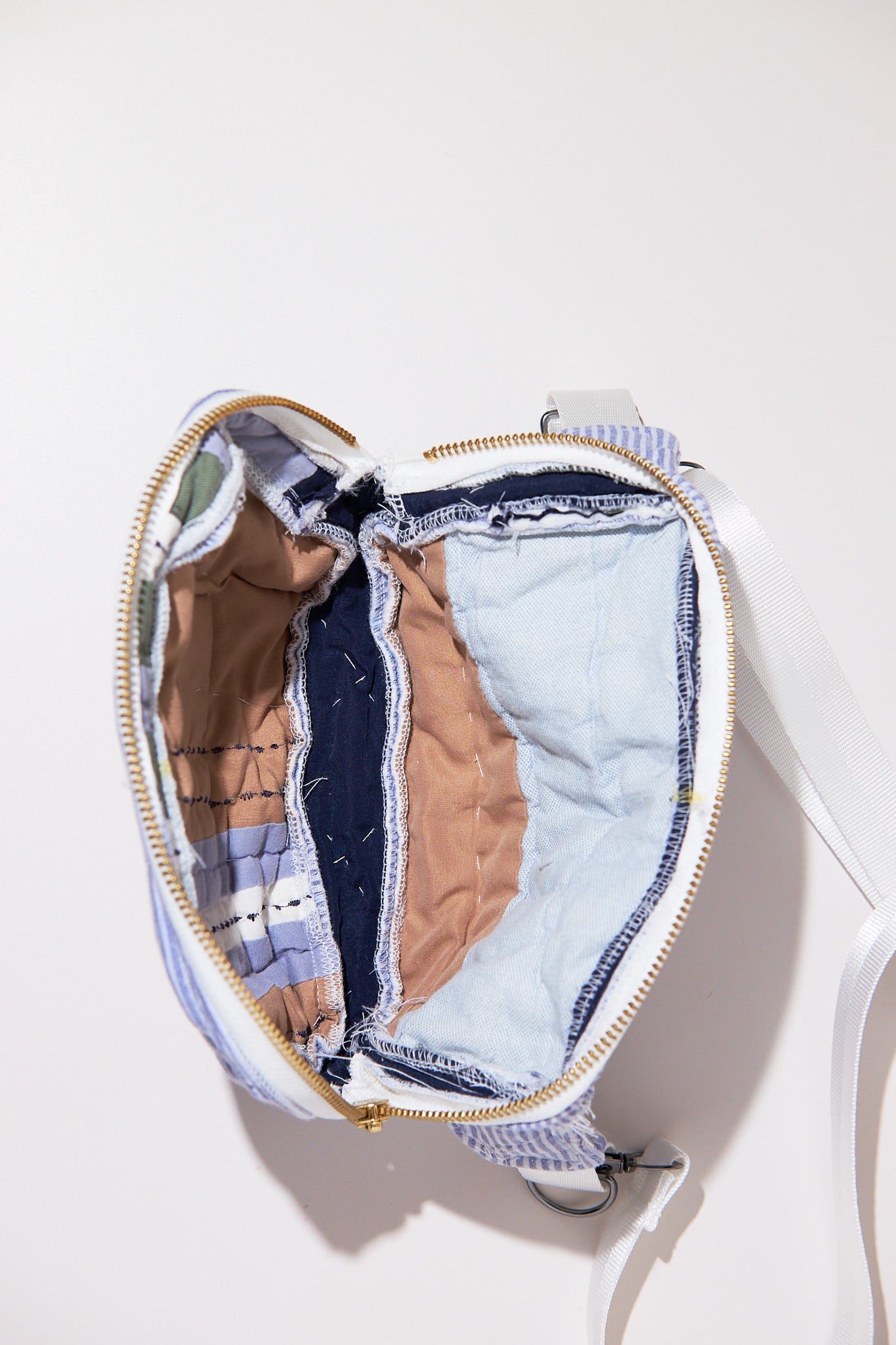Fanny pack / crossbody bag upcycled from comforter open with various patchwork fabrics inside on a white background