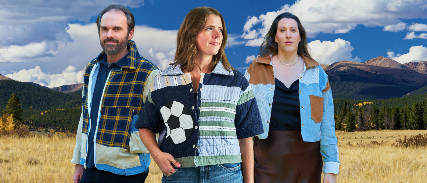 Three people standing outdoors wearing coats from upcycled denim and quilts with a scenic background of mountains and blue sky.